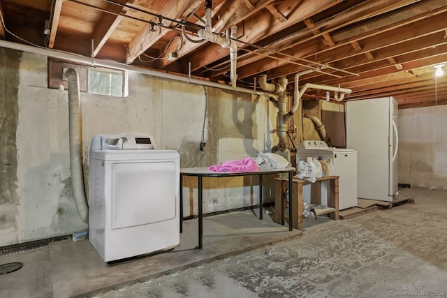 basement featuring washing machine and clothes dryer and freestanding refrigerator