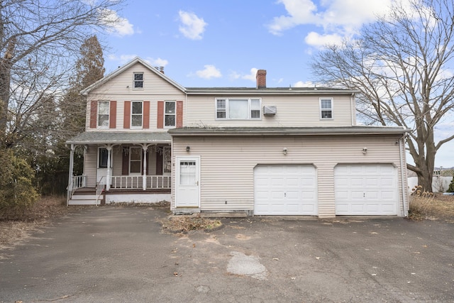 view of front of home with driveway, a garage, a chimney, and a porch