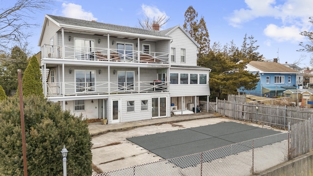 rear view of house with a chimney, a patio area, fence, and a balcony