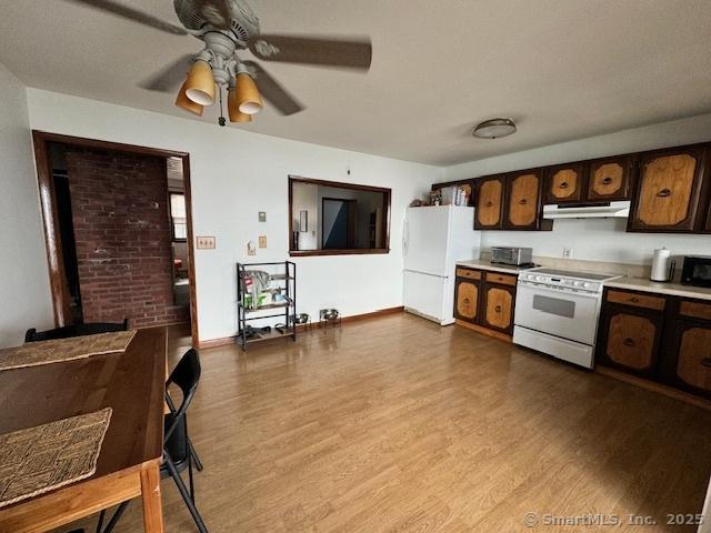 kitchen with dark wood-style floors, light countertops, white appliances, and under cabinet range hood