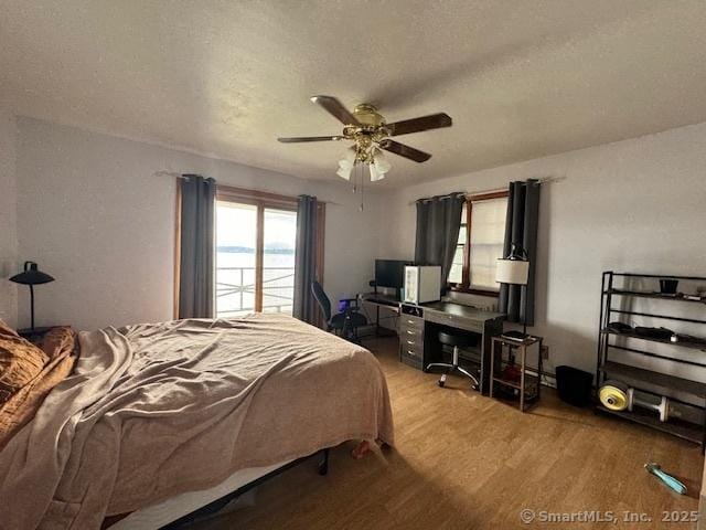 bedroom featuring a textured ceiling, a ceiling fan, and wood finished floors