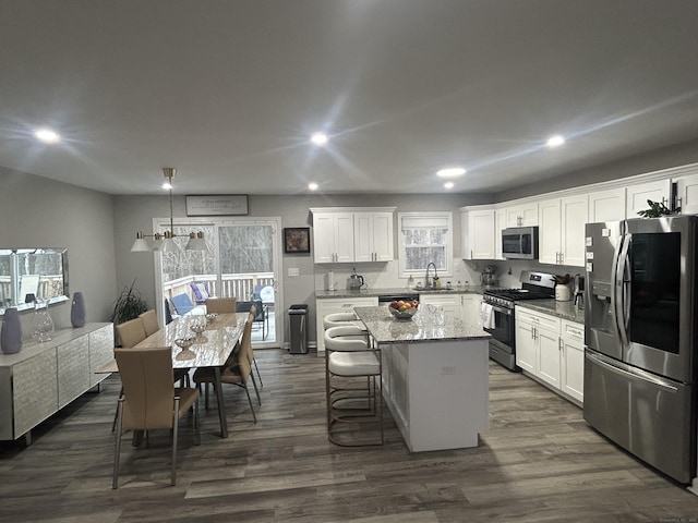 kitchen featuring stainless steel appliances, a center island, white cabinets, and a sink