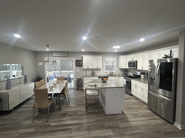 kitchen featuring stainless steel appliances, dark wood-style flooring, a kitchen island, and white cabinetry