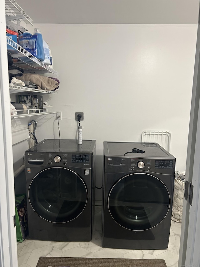 clothes washing area featuring laundry area, marble finish floor, and washing machine and clothes dryer