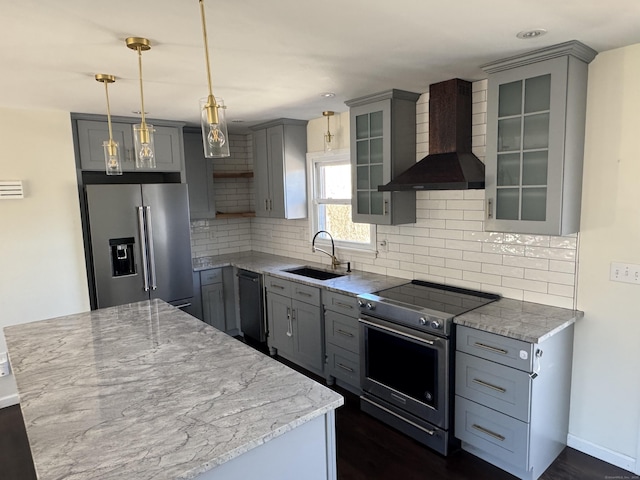 kitchen featuring stainless steel appliances, a sink, wall chimney range hood, gray cabinets, and backsplash