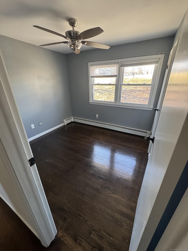 spare room featuring a baseboard radiator, ceiling fan, dark wood-style flooring, and baseboards