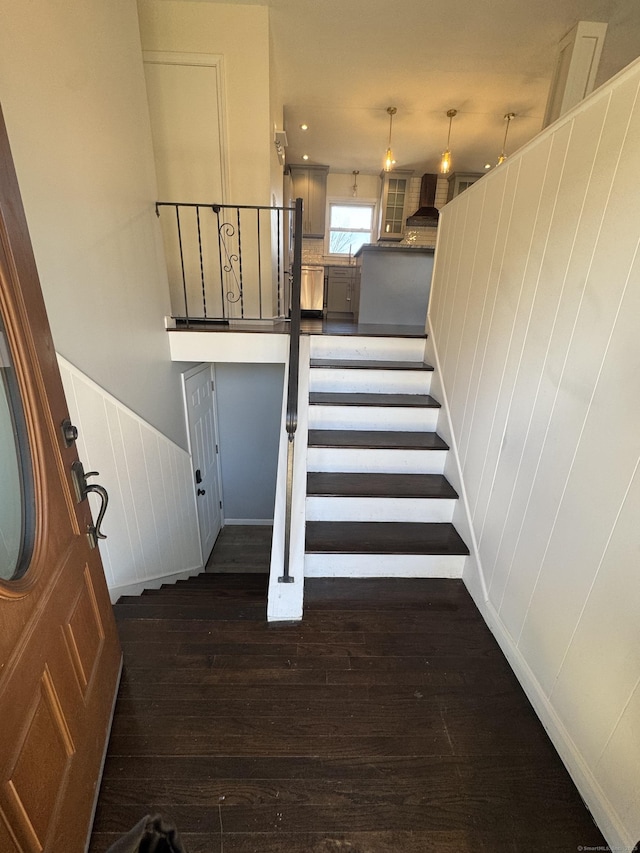 stairs featuring a decorative wall and wood finished floors