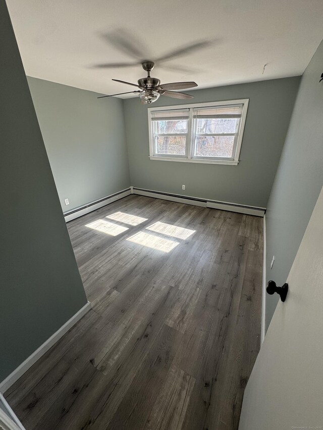 empty room with ceiling fan, a baseboard radiator, wood finished floors, and baseboards