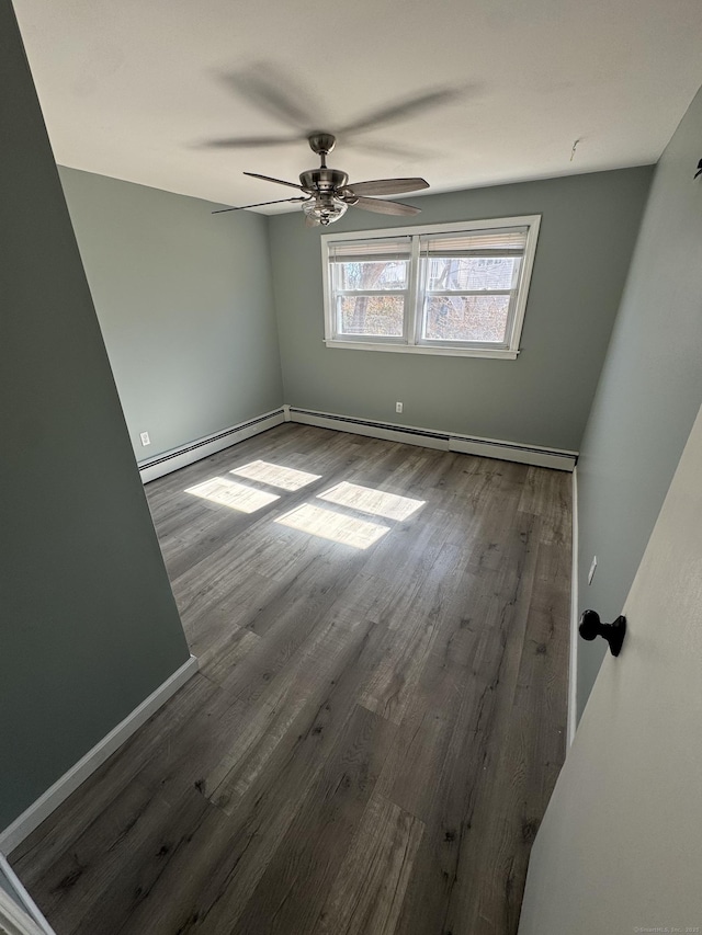 unfurnished room with baseboard heating, baseboards, wood finished floors, and a ceiling fan