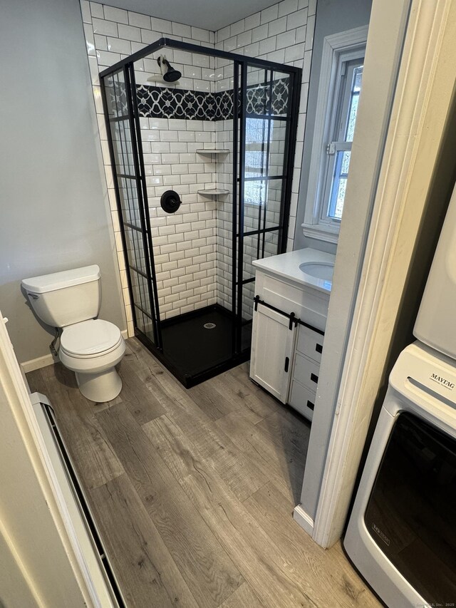 full bath featuring a stall shower, baseboards, toilet, wood finished floors, and vanity