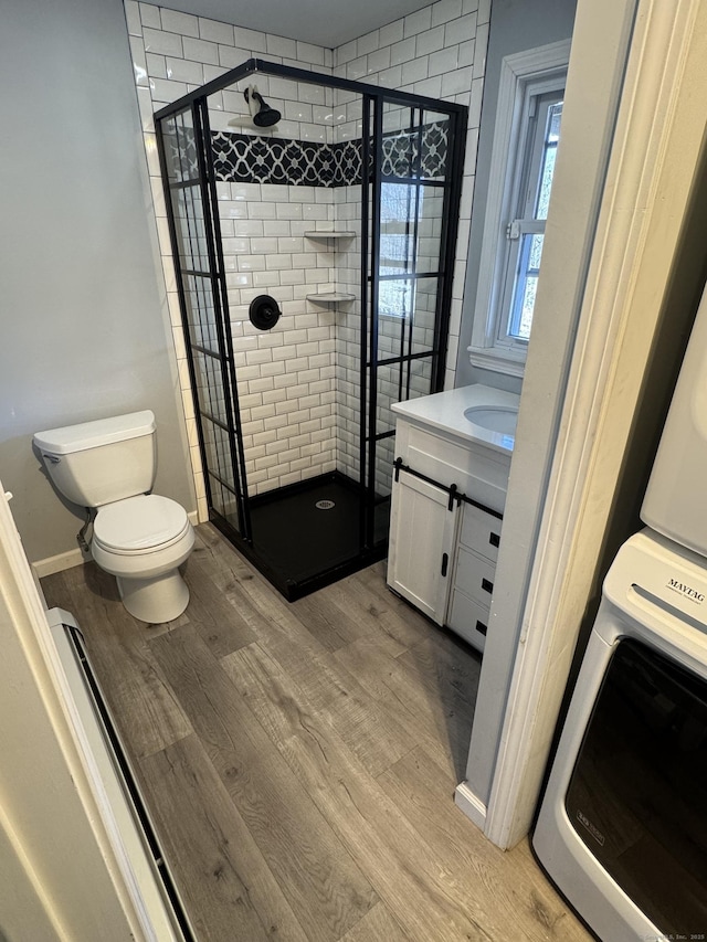 bathroom featuring toilet, vanity, a shower stall, and wood finished floors