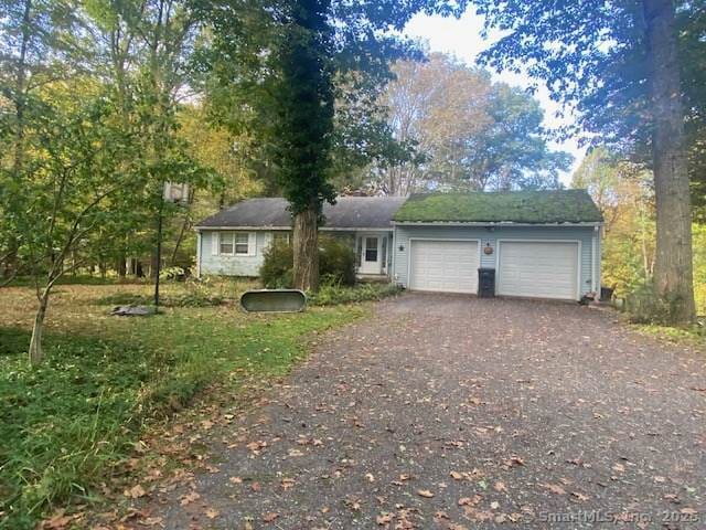 ranch-style house with dirt driveway and a garage