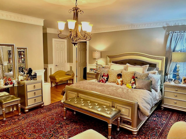 bedroom featuring an inviting chandelier, ornamental molding, wood finished floors, and wainscoting