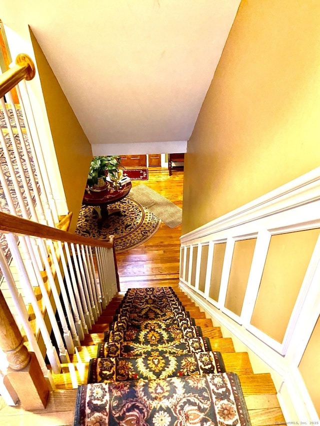 stairway featuring vaulted ceiling and wood finished floors