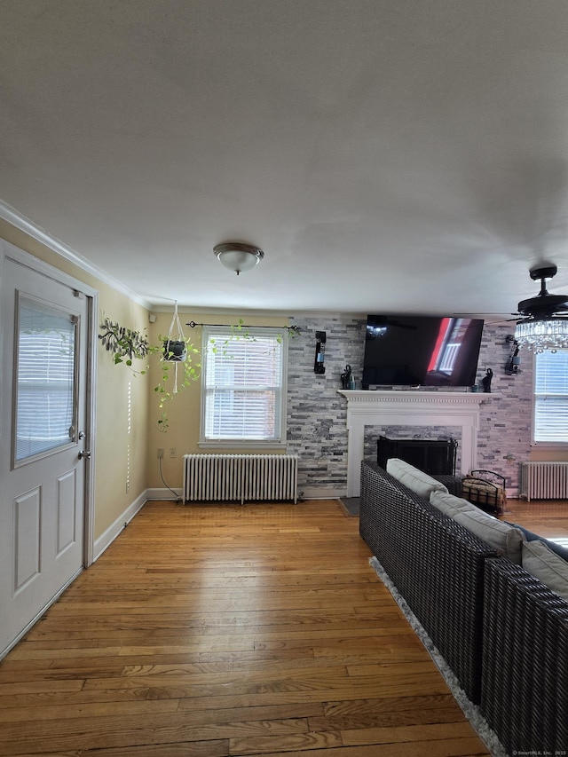 unfurnished living room with a healthy amount of sunlight, a premium fireplace, wood finished floors, and radiator