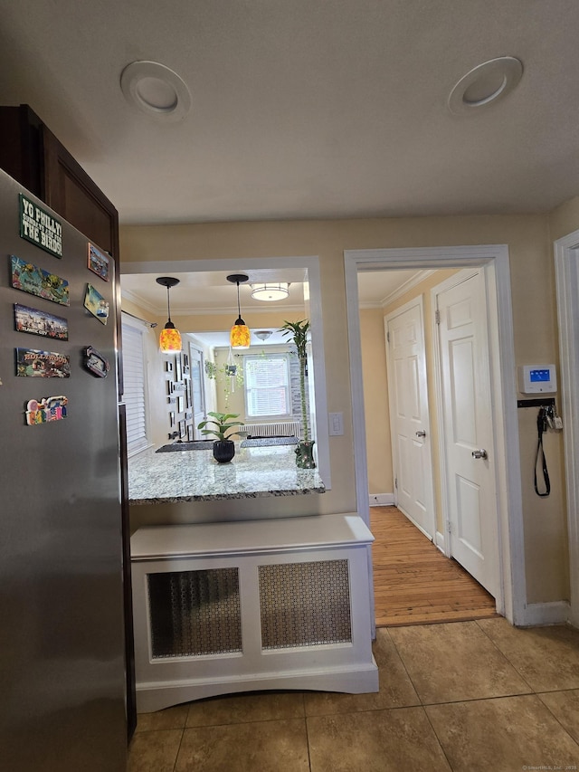 kitchen featuring decorative light fixtures, light countertops, ornamental molding, freestanding refrigerator, and tile patterned floors