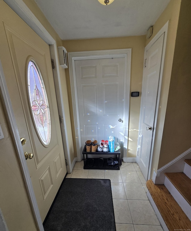 entryway with light tile patterned floors, stairway, and baseboards