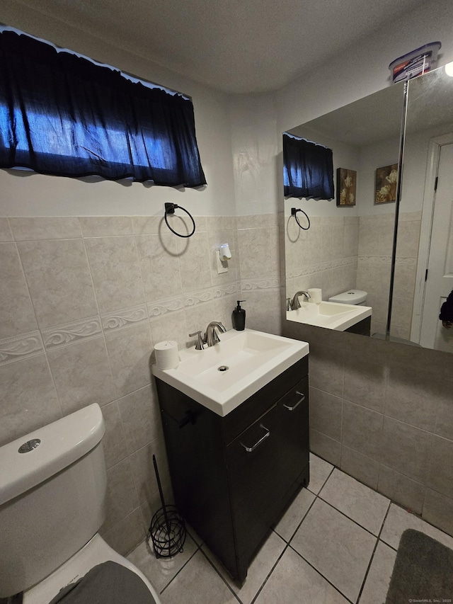 half bath with toilet, tile patterned flooring, and vanity