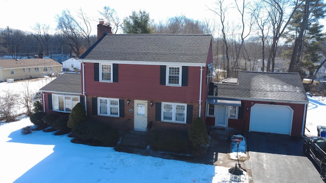 view of front of home with aphalt driveway, brick siding, roof with shingles, a chimney, and an attached garage