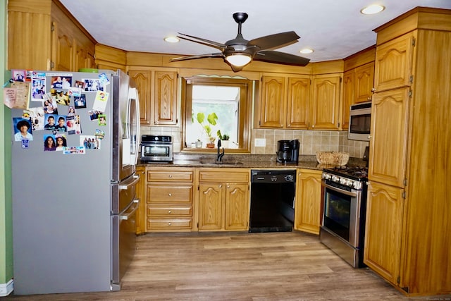 kitchen with ceiling fan, stainless steel appliances, a sink, light wood-style floors, and decorative backsplash