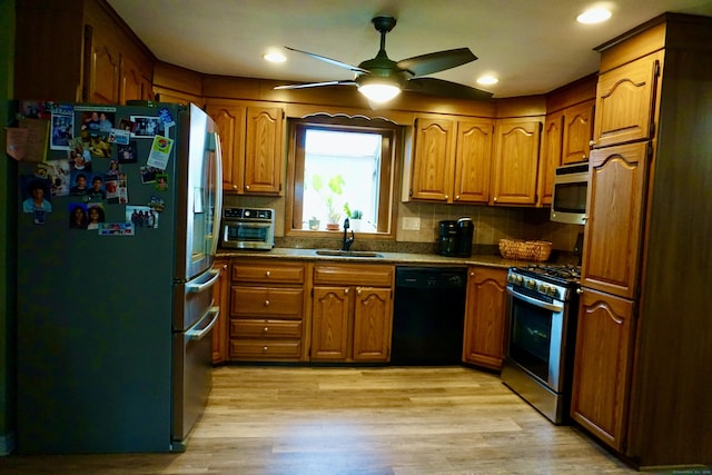 kitchen featuring brown cabinets, a sink, stainless steel appliances, light wood-type flooring, and backsplash