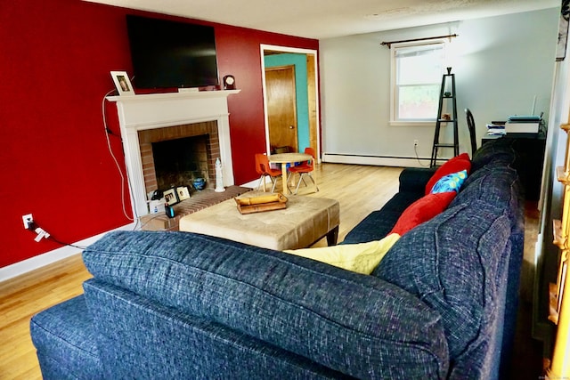 living area featuring baseboard heating, a fireplace, baseboards, and wood finished floors