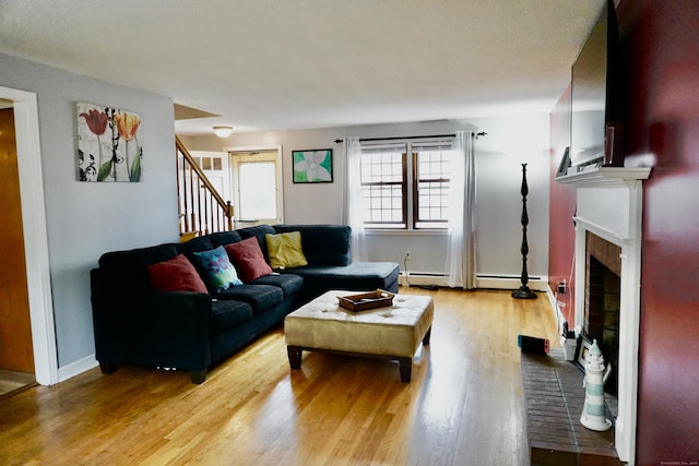 living area with stairway, a fireplace, light wood-style flooring, and baseboards