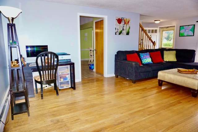 living room with a textured ceiling, stairway, and light wood-style floors