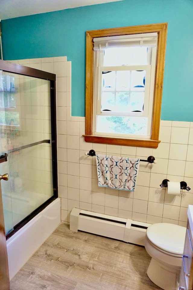 bathroom with tile walls, baseboard heating, toilet, enclosed tub / shower combo, and wood finished floors