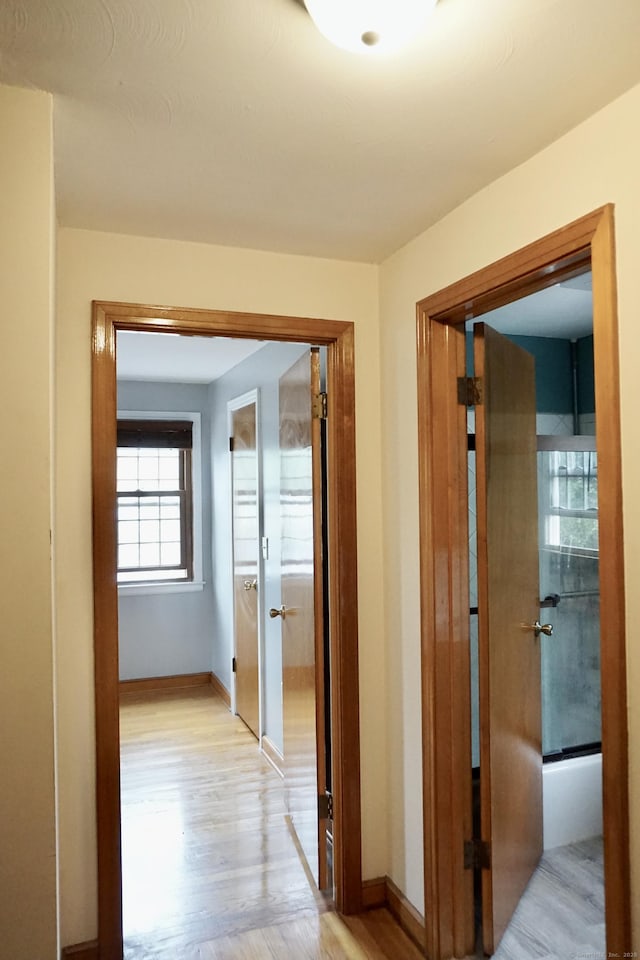 corridor with light wood finished floors and baseboards