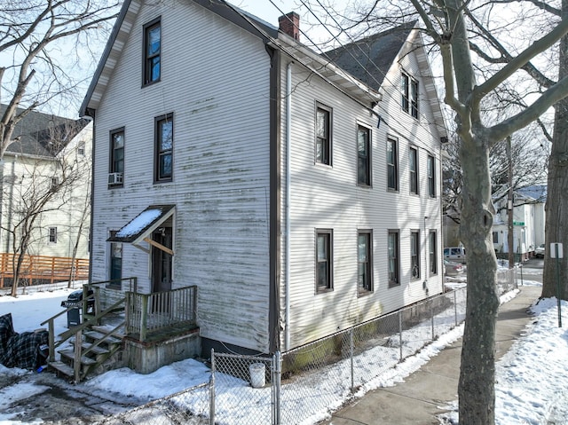 view of snow covered exterior with fence and a chimney