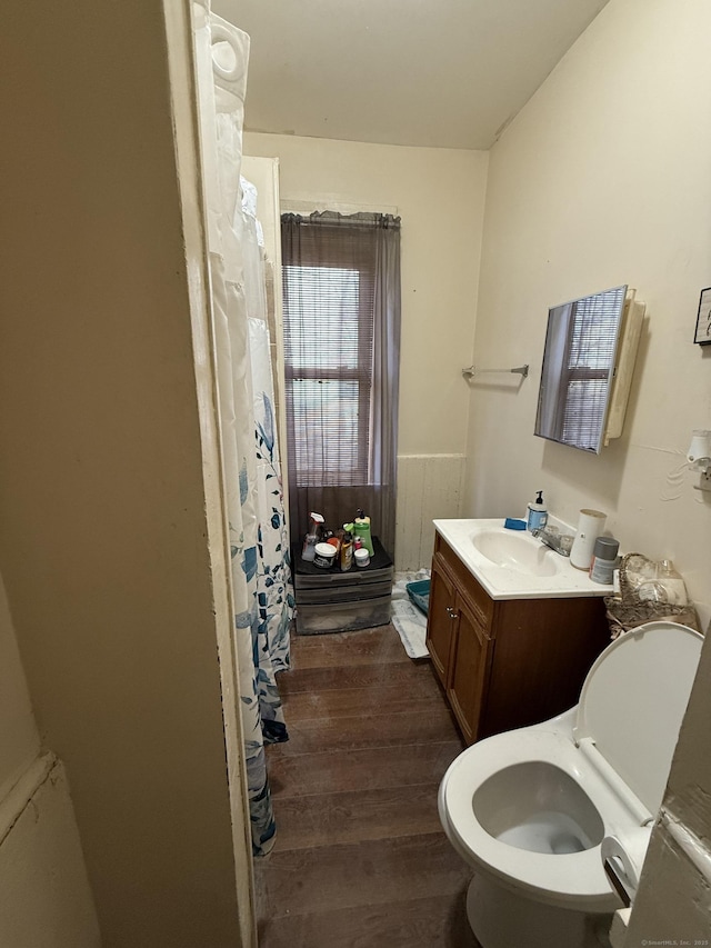 full bath featuring toilet, a wainscoted wall, wood finished floors, curtained shower, and vanity