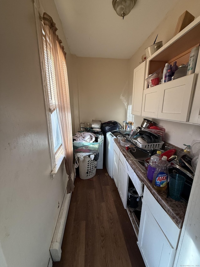 kitchen with dark wood finished floors, open shelves, dark countertops, white cabinets, and washer / dryer