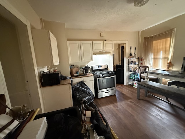 kitchen with a textured ceiling, stainless steel gas range oven, under cabinet range hood, dark wood-style flooring, and white cabinetry