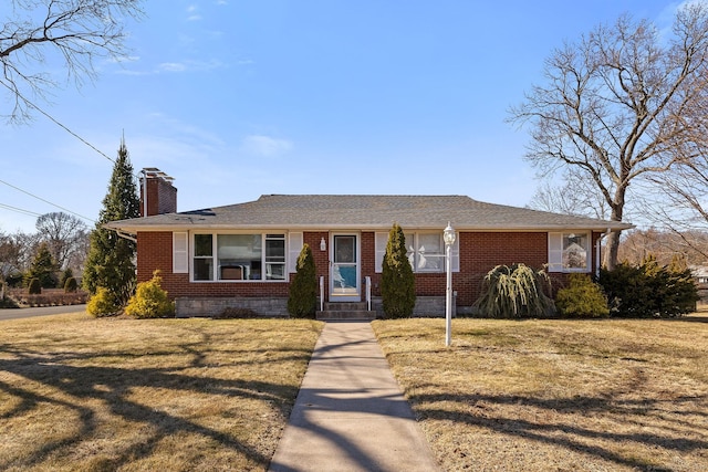 ranch-style house featuring a chimney, a front yard, and brick siding