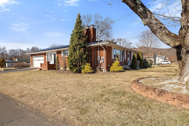 ranch-style home with an attached garage, a chimney, a front lawn, concrete driveway, and brick siding