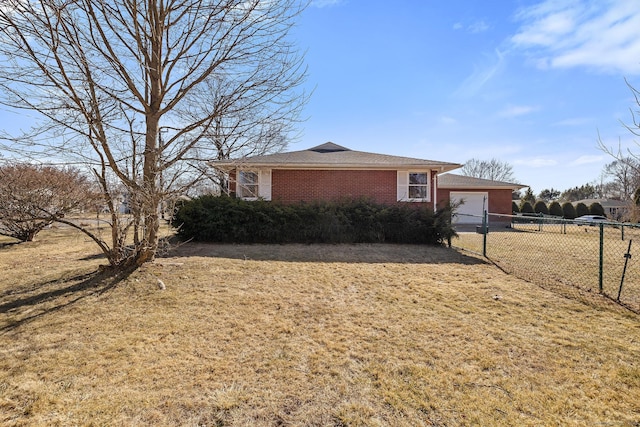 view of side of home featuring brick siding, an attached garage, fence, and a yard