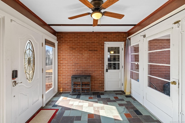 interior space featuring brick wall, ceiling fan, and dark floors