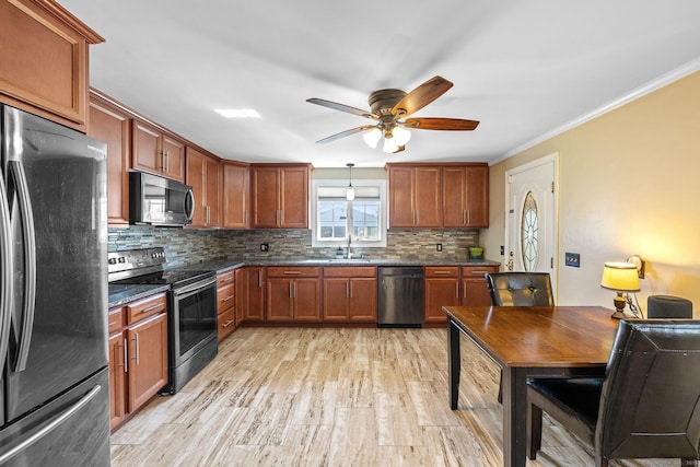 kitchen with tasteful backsplash, crown molding, dark stone counters, light wood-type flooring, and appliances with stainless steel finishes