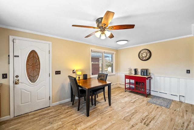 dining space featuring light wood finished floors, baseboard heating, a ceiling fan, and ornamental molding