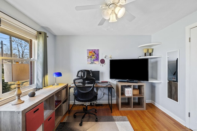 office area with a ceiling fan, wood finished floors, and baseboards