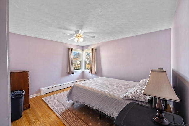 bedroom featuring ceiling fan, baseboard heating, light wood finished floors, a textured ceiling, and baseboards