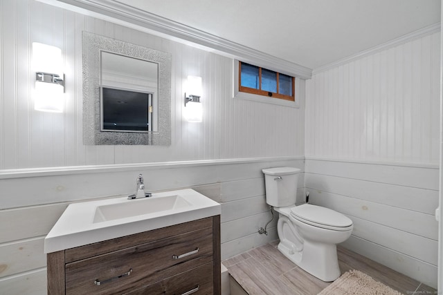 bathroom with wood finished floors, toilet, ornamental molding, and vanity