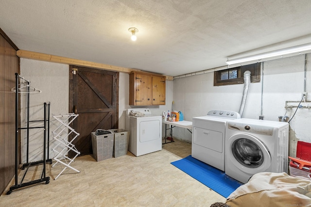 washroom featuring a textured ceiling, cabinet space, independent washer and dryer, and light floors