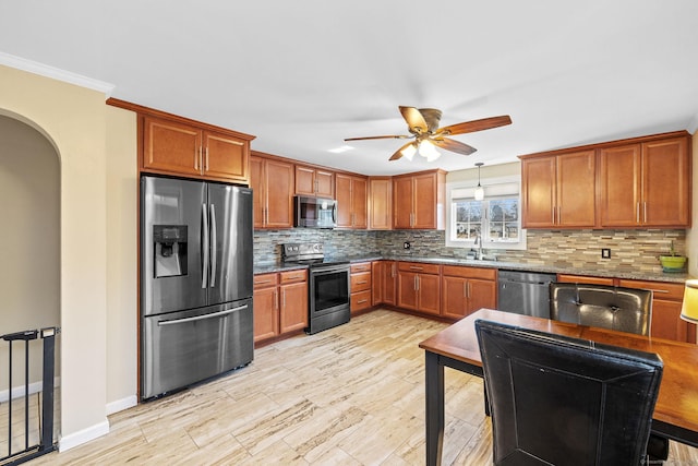 kitchen with decorative backsplash, light wood-style floors, ceiling fan, arched walkways, and appliances with stainless steel finishes