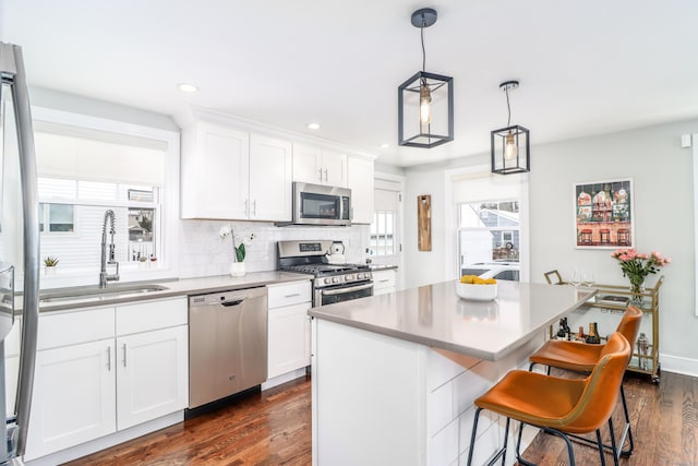 kitchen featuring stainless steel appliances, backsplash, dark wood-type flooring, white cabinetry, and a sink