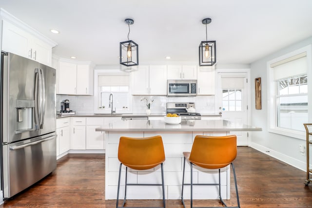 kitchen with appliances with stainless steel finishes, a sink, white cabinets, and a healthy amount of sunlight