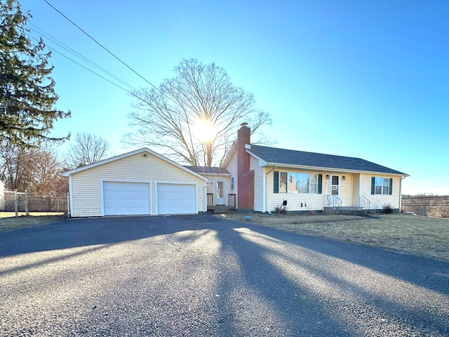 ranch-style home featuring a chimney, a detached garage, and fence