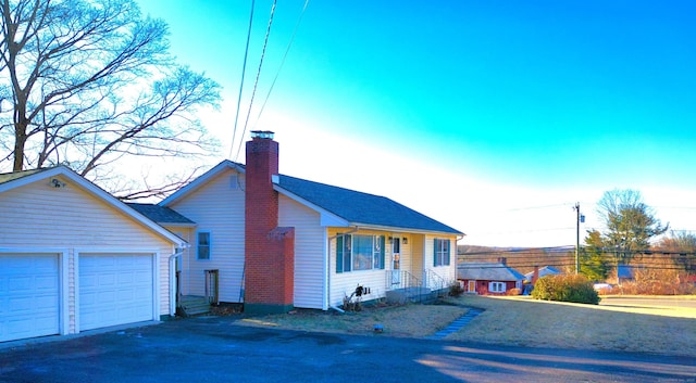 view of front facade featuring a garage, roof with shingles, and a chimney