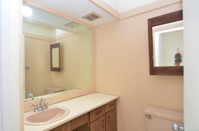 bathroom featuring visible vents, toilet, and vanity